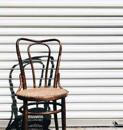 brown wooden chair beside white wall