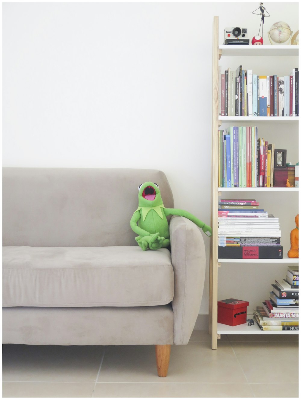 The Muppets Kermit plush toy on gray sofa