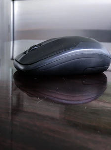 Modern wireless mouse on a reflective white surface with subtle shadows and a premium look.