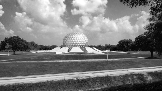 A warm geodesic dome nestled in a lush green landscape under a soft sunset sky.