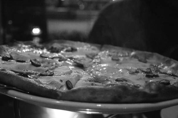 A cozy setting with a steaming hot pizza and a side of crispy chicken wings on a black plate