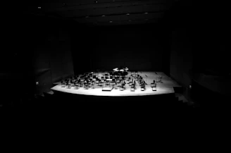 A distinguished concert hall stage with Gil Tower poised with his flute, bathed in warm spotlight.