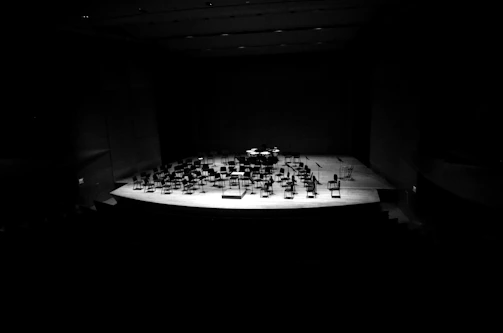 A distinguished concert hall stage with Gil Tower poised with his flute, bathed in warm spotlight.