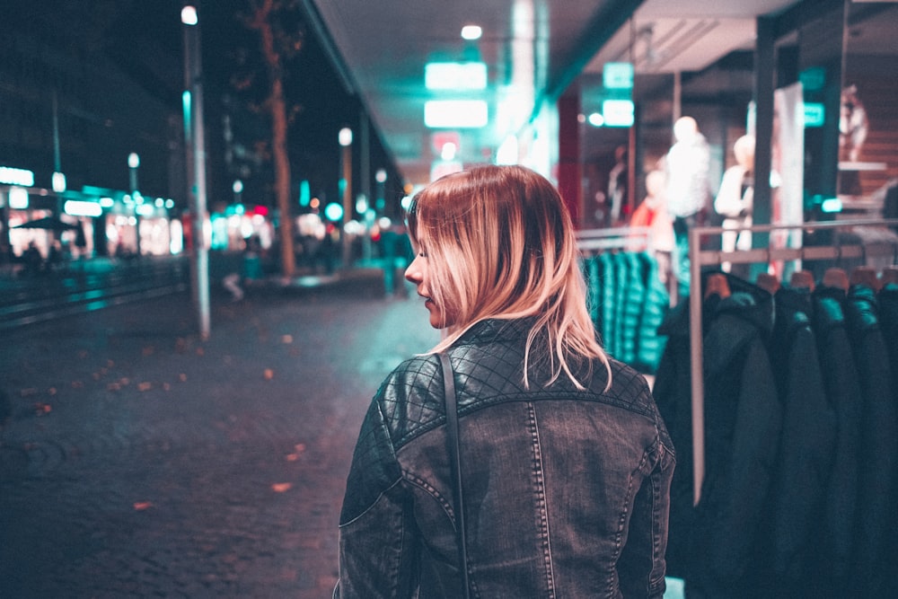 woman in black jacket walking along the street