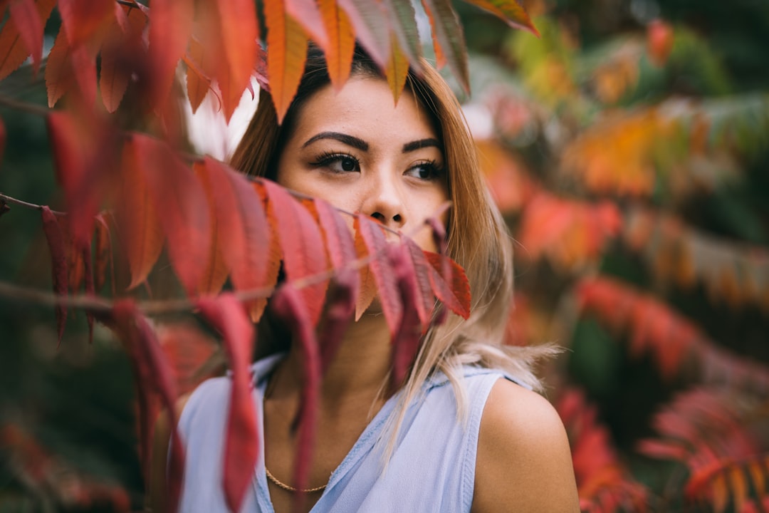 woman in white top standing outdoors surrounded by trees