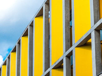 Close-up of a brutalist concrete structure with sharp shadows and vibrant yellow accents.