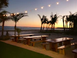 Sunset over a serene beach in Bali with a picnic spread of tropical fruits and healthy snacks.