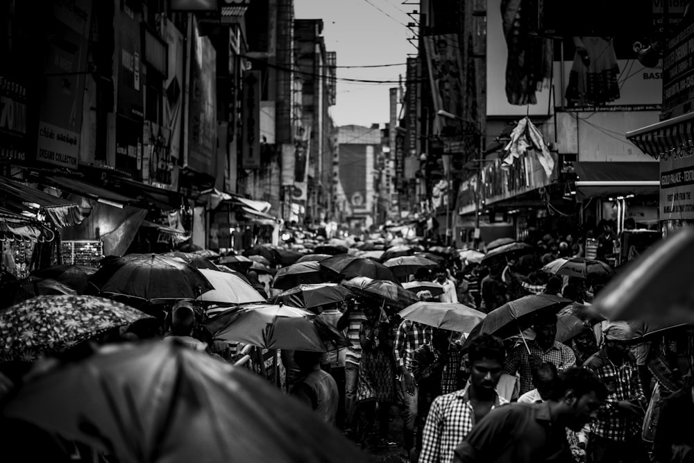 fotografia in scala di grigi di gruppo di persone che tengono l'ombrello