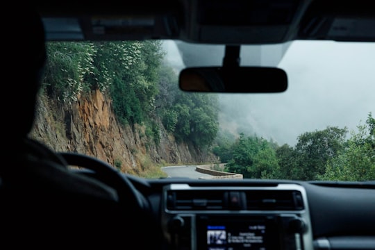 person driving vehicle beside cliff during daytime in Sequoia National Forest United States