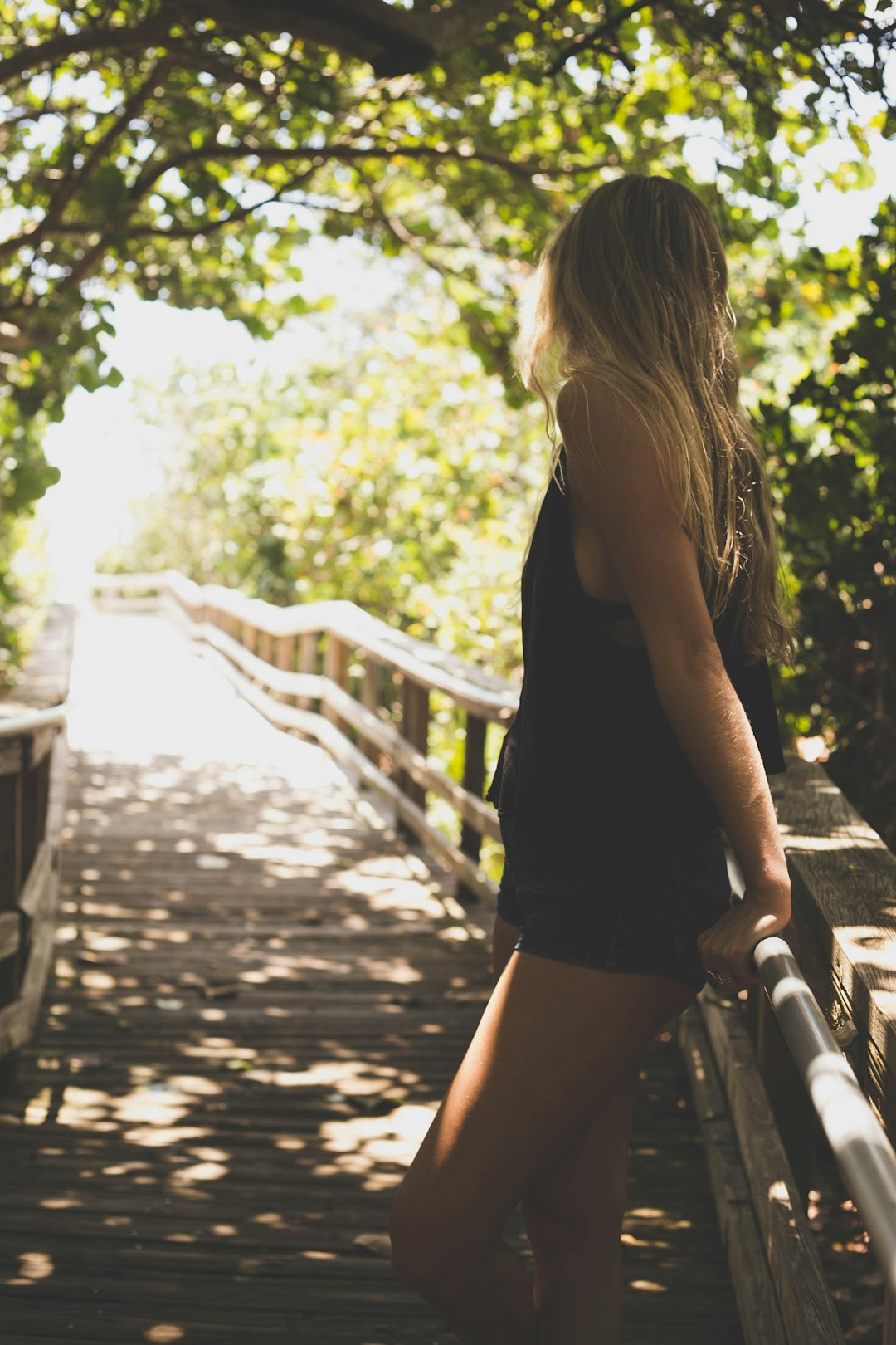 woman leaning on handrail between trees