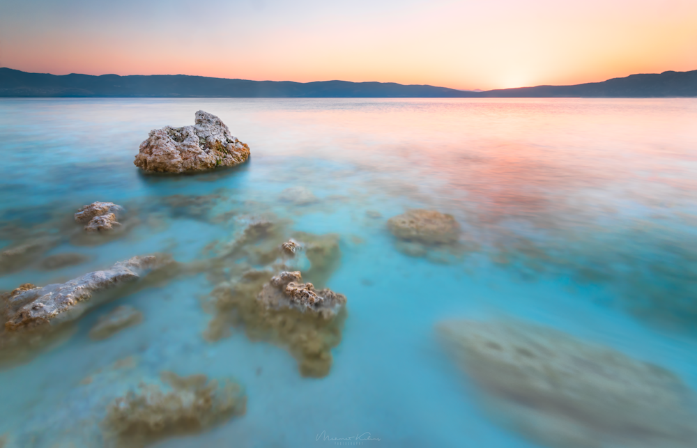 grey and brown cliff surrounded body of water during sunset