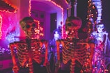 two skeleton near white concrete building with string lights at daytime