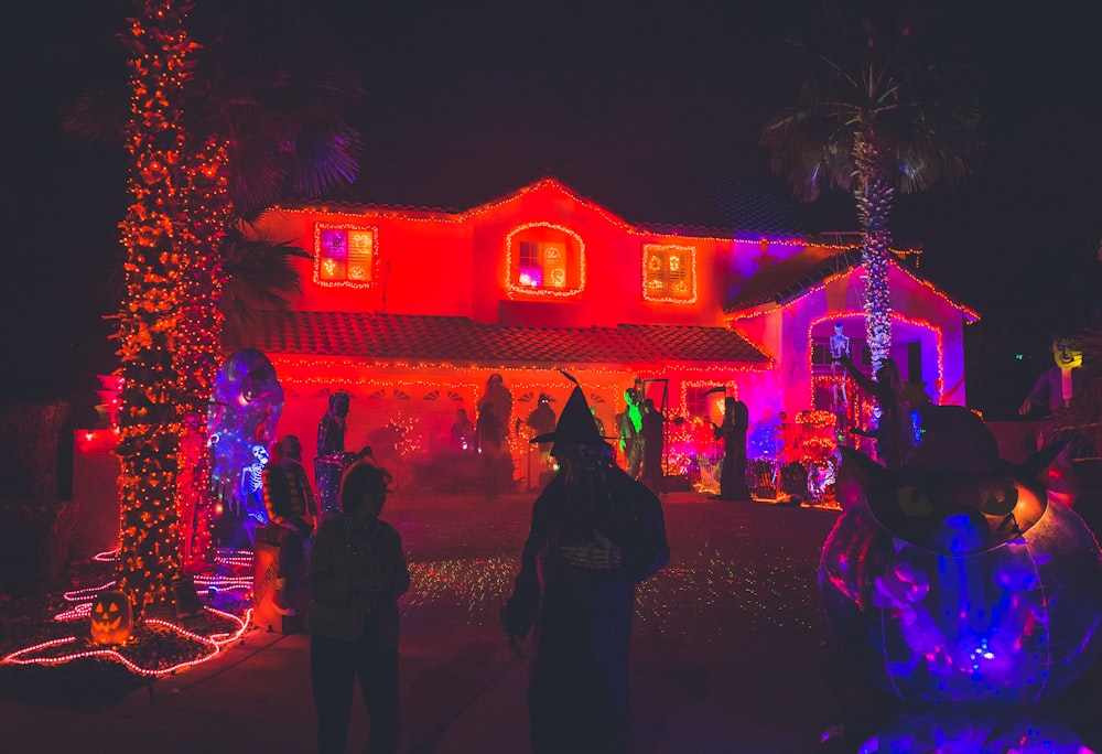 pessoas em pé perto de casa com decoração de luz vermelha durante a noite
