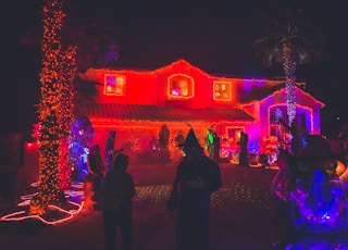 people standing near house with red light decor during night time