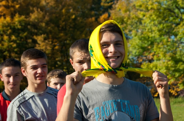A group of young volunteers planting trees together, full of smiles and energy under a bright sky.