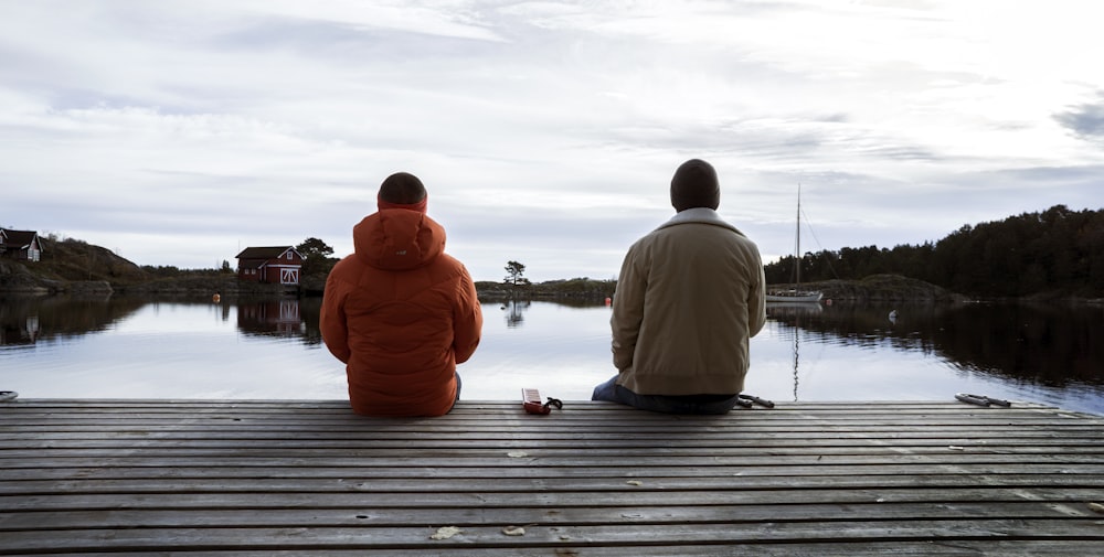 2 men sitting on dock during daytime