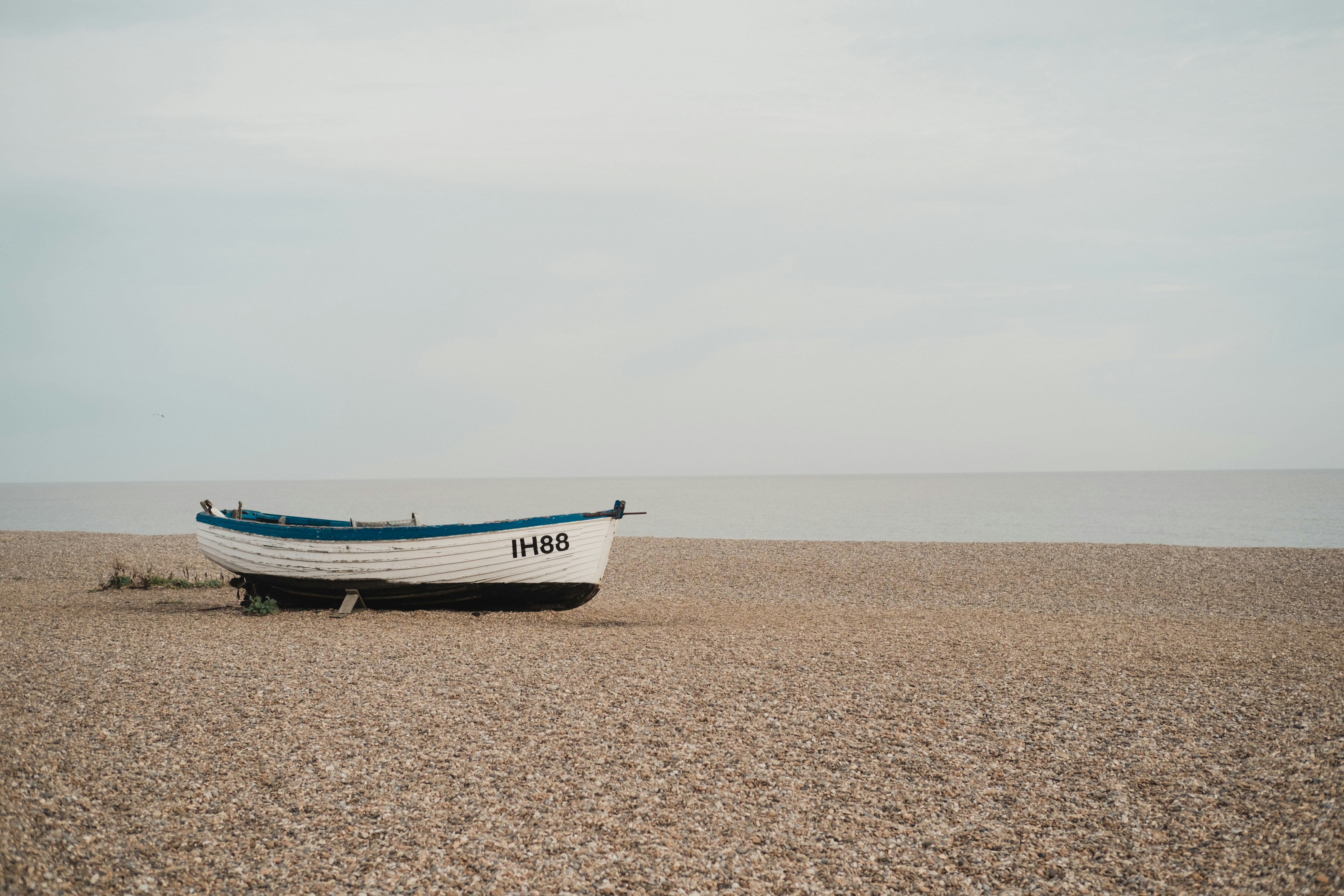 chaloupe IH88 blanche et bleue sur le sable au bord d’un grand plan d’eau