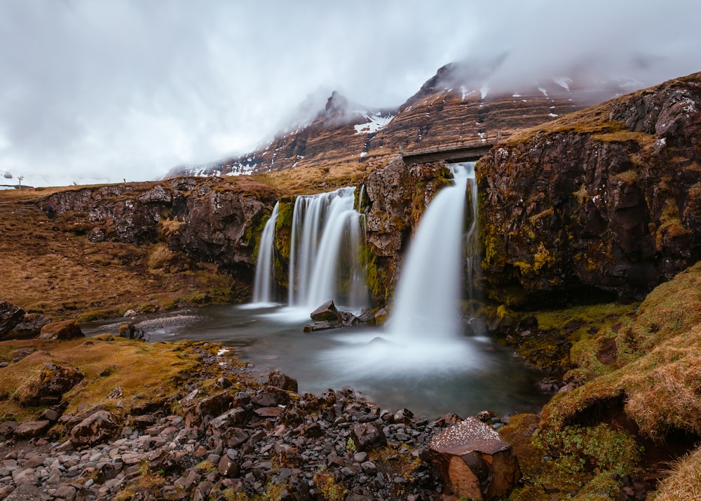 waterfalls surround brown cliff during daytime