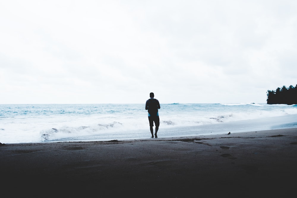 man standing beside seashore