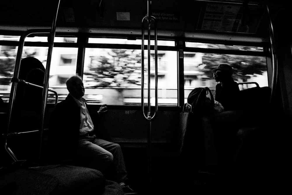 grayscale photo of several people on moving train