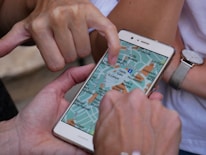 Close-up of hands using a tablet showing a digital map of a neighborhood.