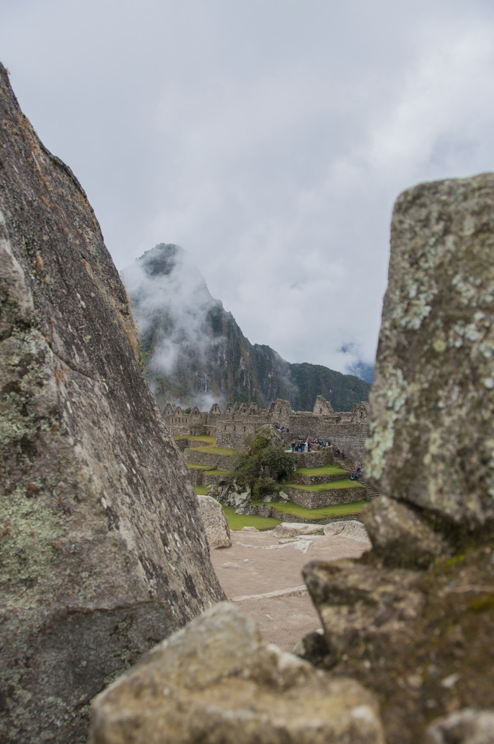 people standing on rock formation under white clouds