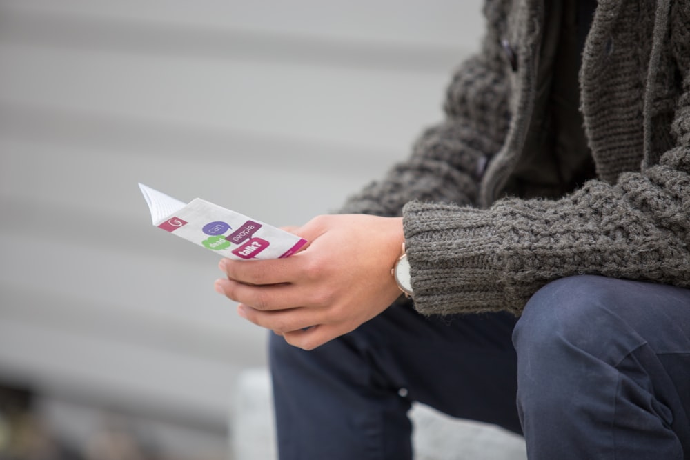 personne tenant blanc et multicolore papier blanc assis