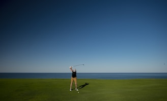 man standing on green grass field playing golf