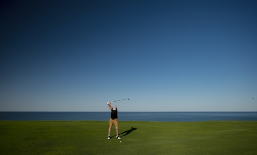 man standing on green grass field playing golf