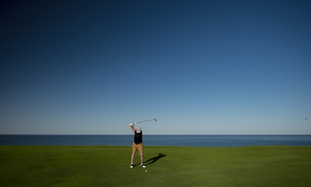 man standing on green grass field playing golf