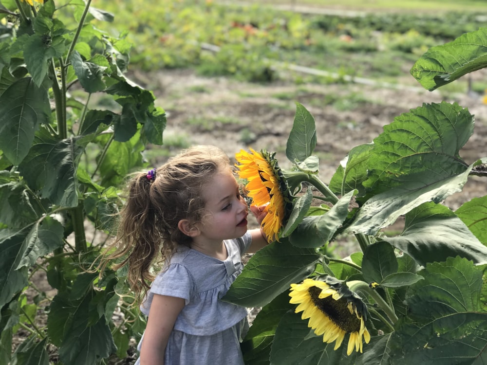 Foto di messa a fuoco selettiva della ragazza che sente l'odore del girasole