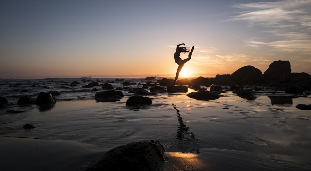 silhouette photography of woman standing on rock