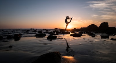 silhouette photography of woman standing on rock dancer teams background