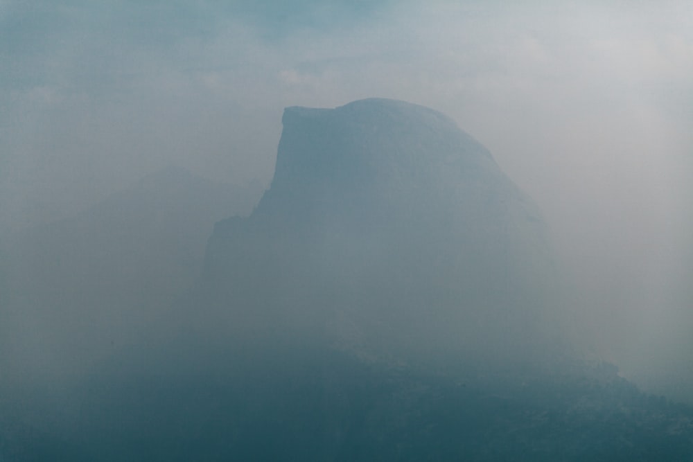 a mountain in the fog with a sky background