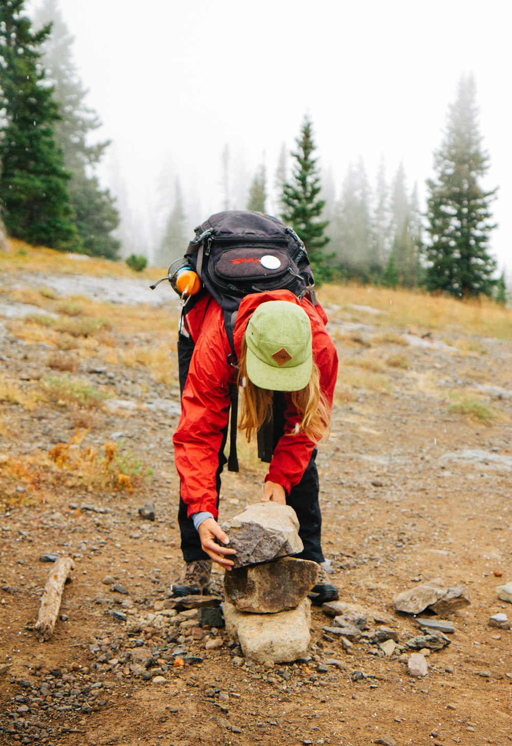 woman wearing red jacket holding rocks standing near green trees