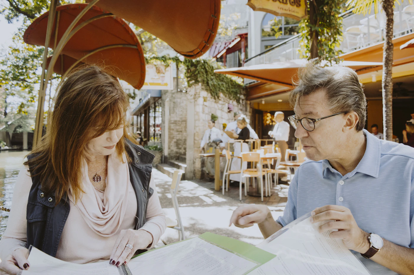 Two people reviewing papers together at an outdoor cafe table