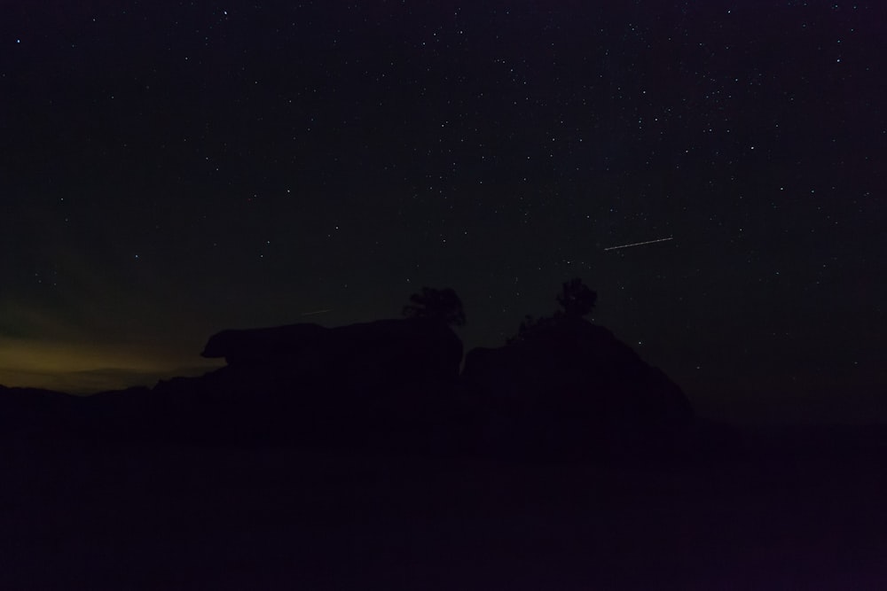 the night sky with stars above a rock formation