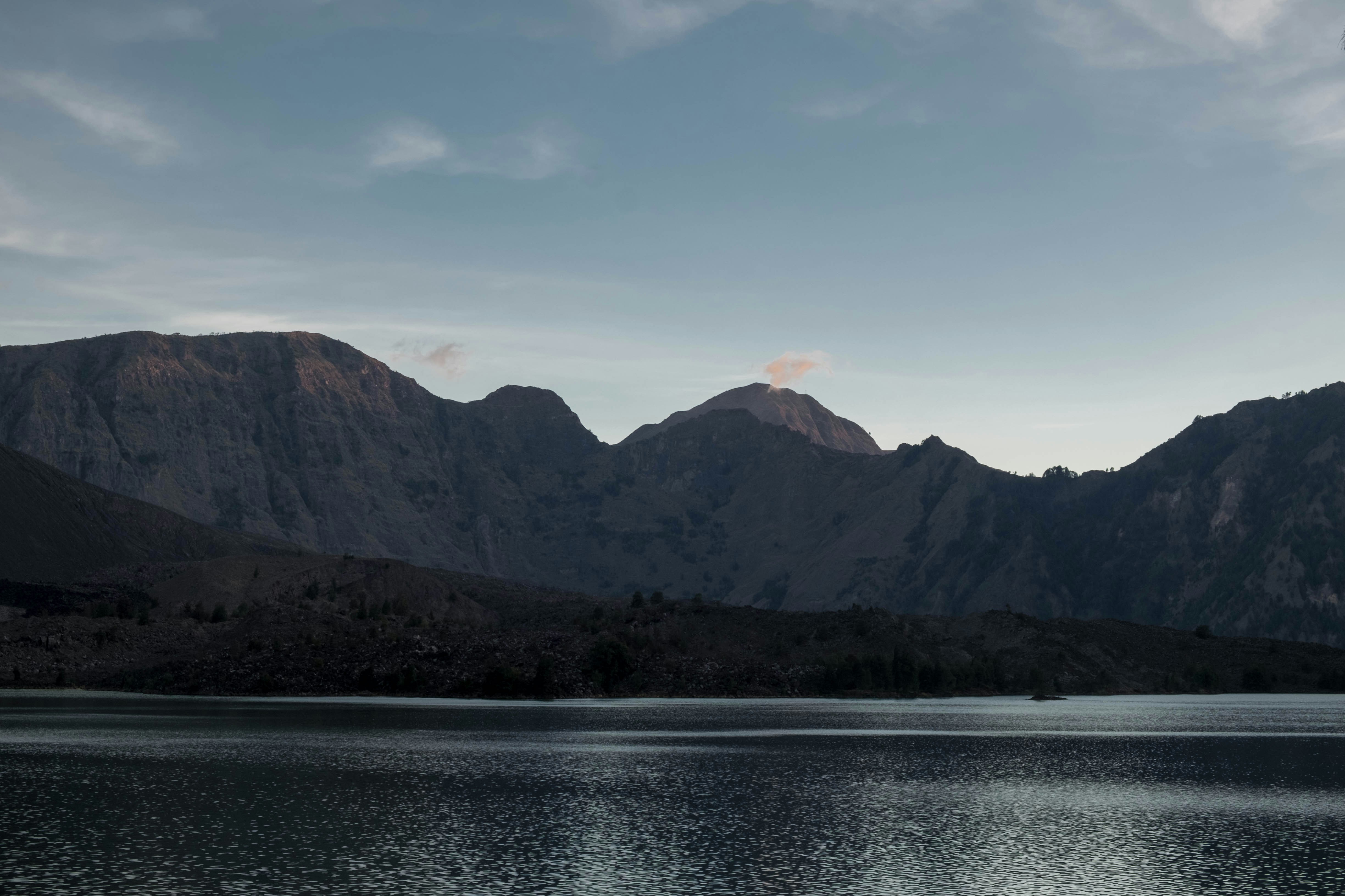 Serene Lake Arenal reflecting the surrounding mountains and sky in early morning light.