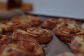 A warm, inviting shot of a cinnamon roll fresh out of the oven, with icing dripping down the sides.