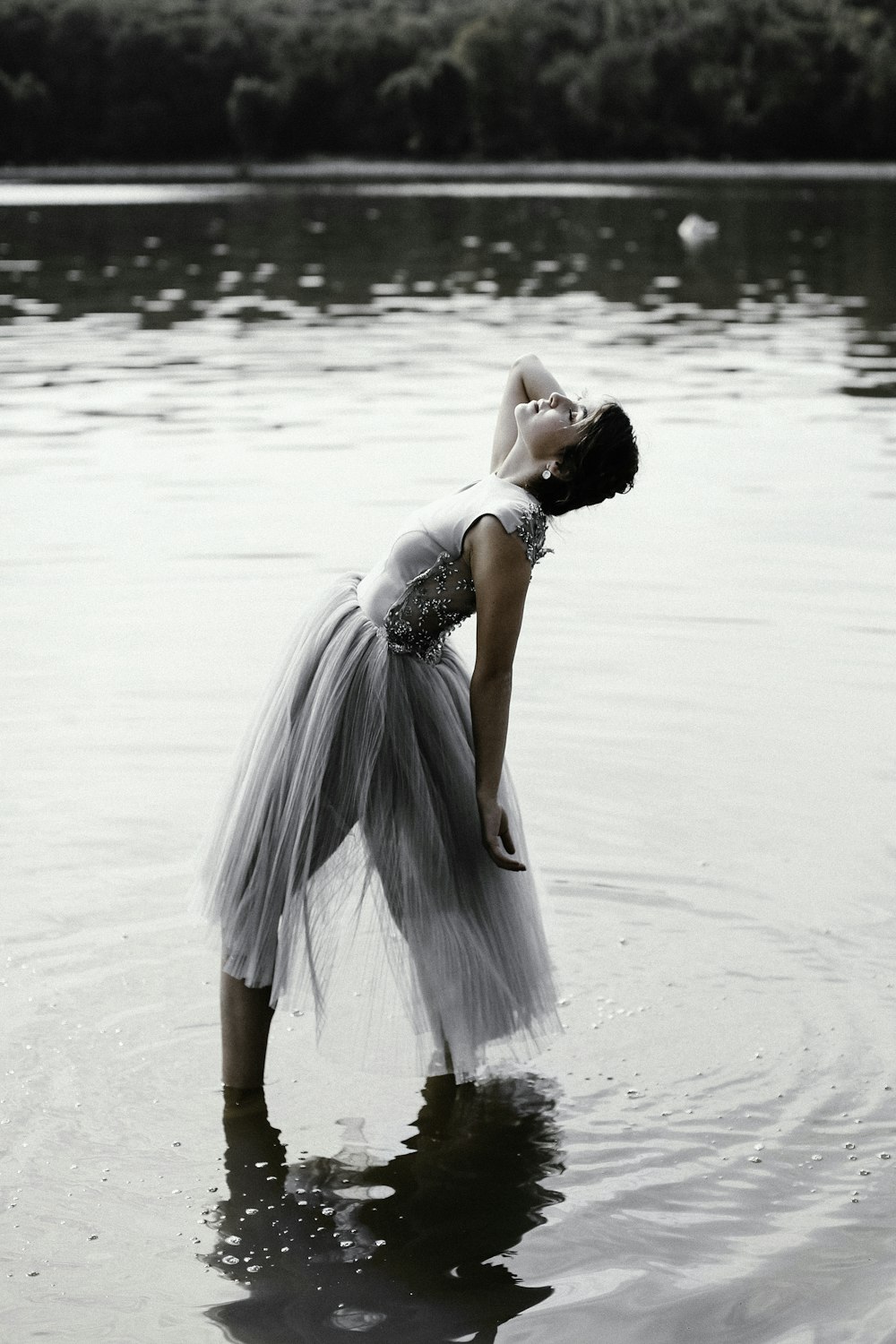 얕은 물 위에 서 있는 회색 드레스를 입은 여자