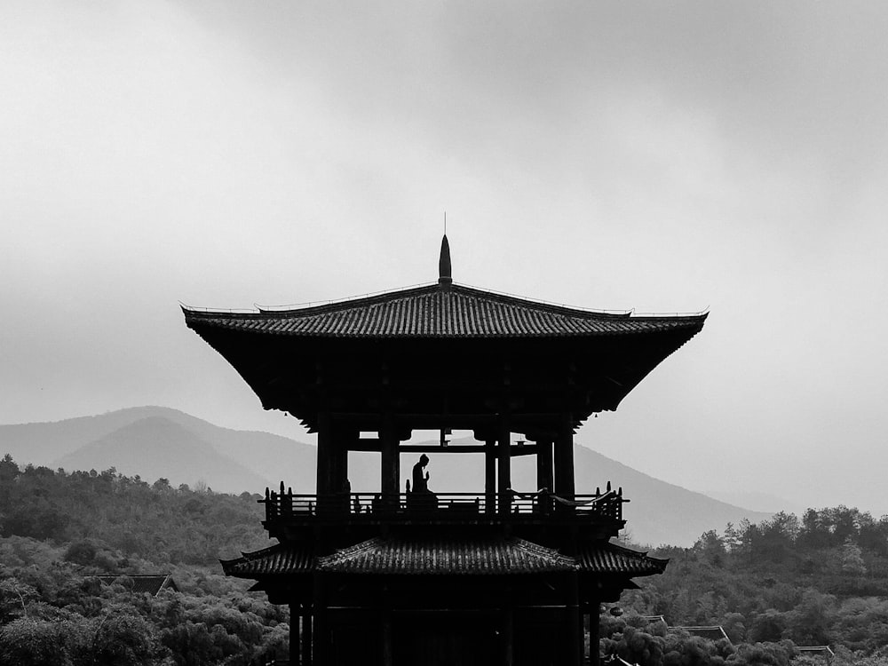 grayscale photography of person on pagoda