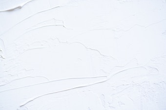 White textured surface with smooth and rough patches, possibly resembling thick paint or plaster applied onto a flat surface. The surface has visible brush or tool marks, creating a sense of movement and dimension.