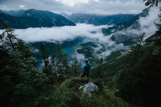 person standing on green cliff under blue sky in Königssee Germany