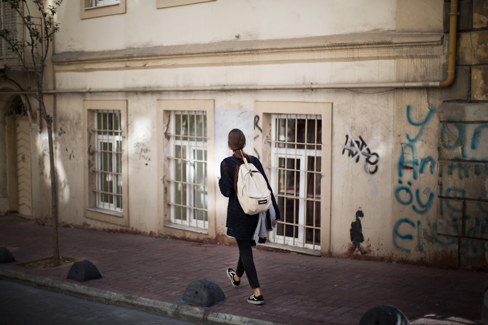 woman walking on sidewalk nearby beige structure