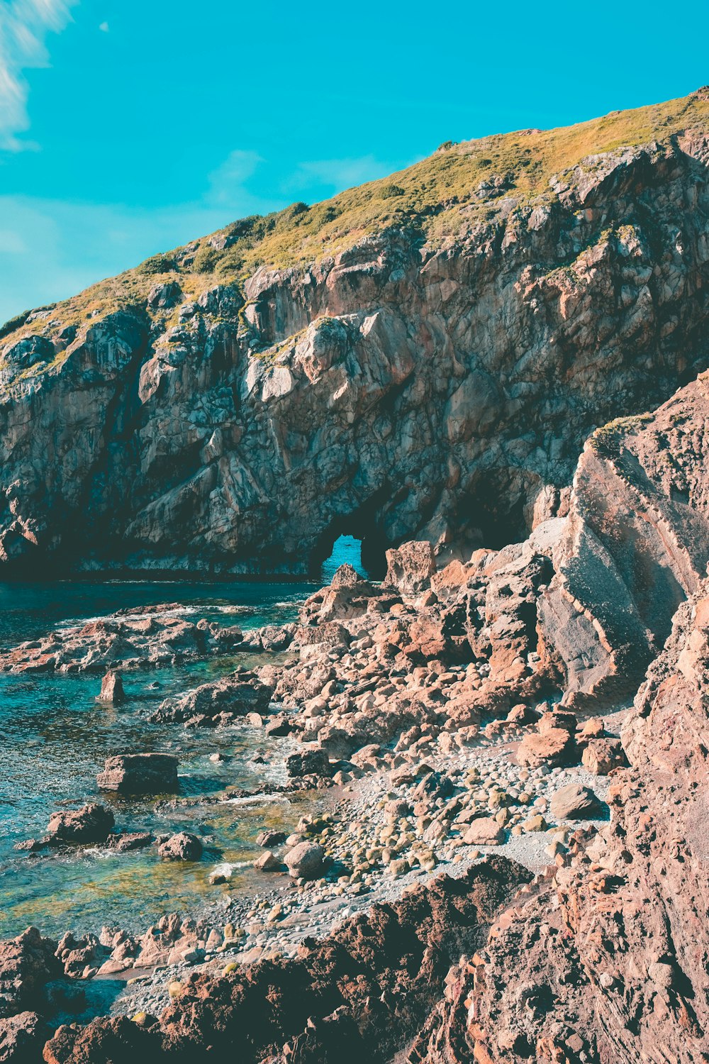 a rocky beach with a small cave in the middle of it