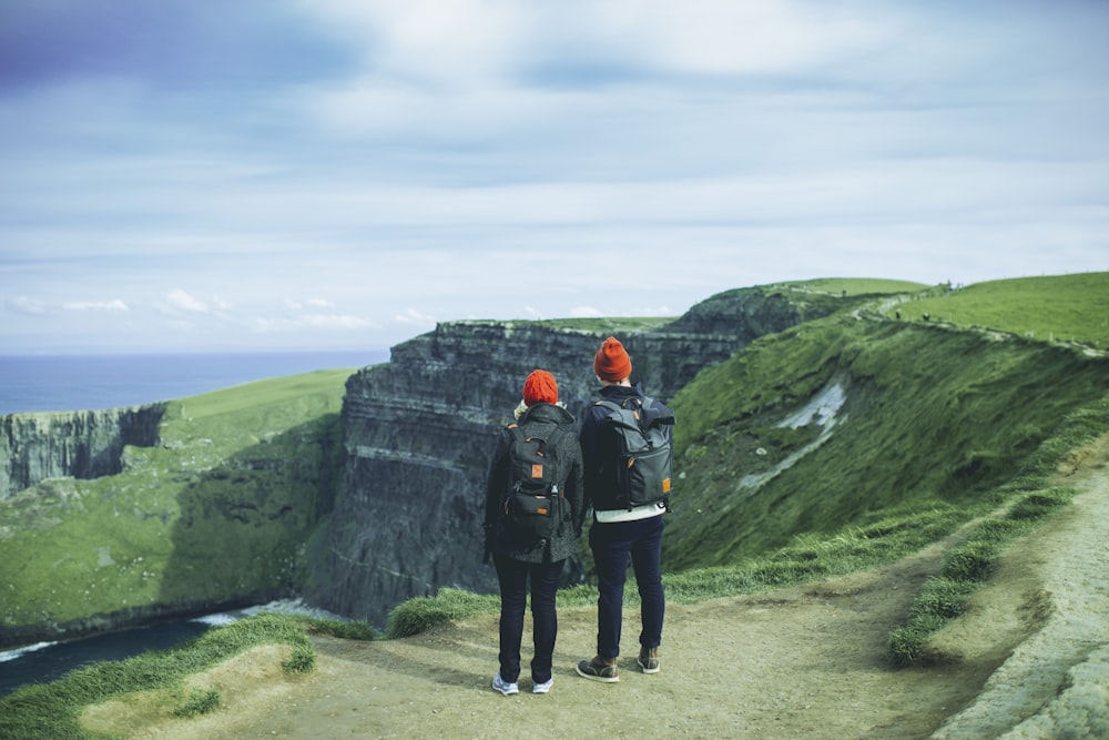 two person looking on mountain cliff near river