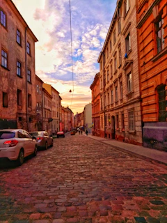 A charming cobblestone street lined with colorful historic buildings in Prague at sunset.