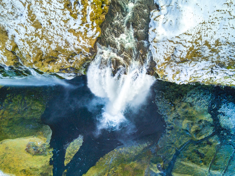 Photographie en plongée de chutes d’eau entre de gros rochers pendant la journée