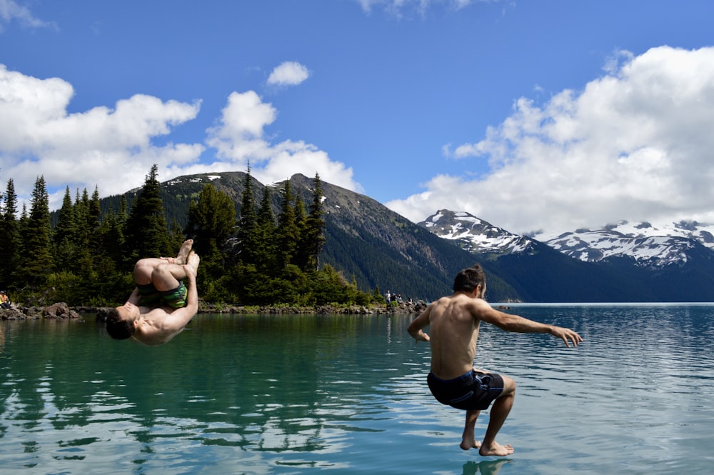 a man diving into a lake while another man watches
