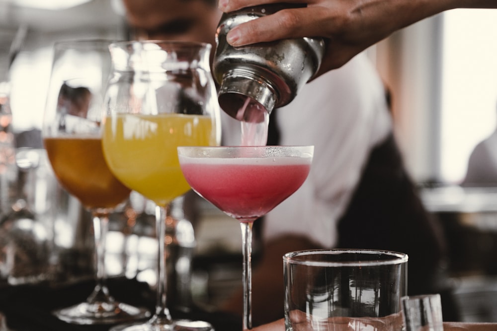 personne tenant un shaker versant du liquide dans un verre pendant la journée